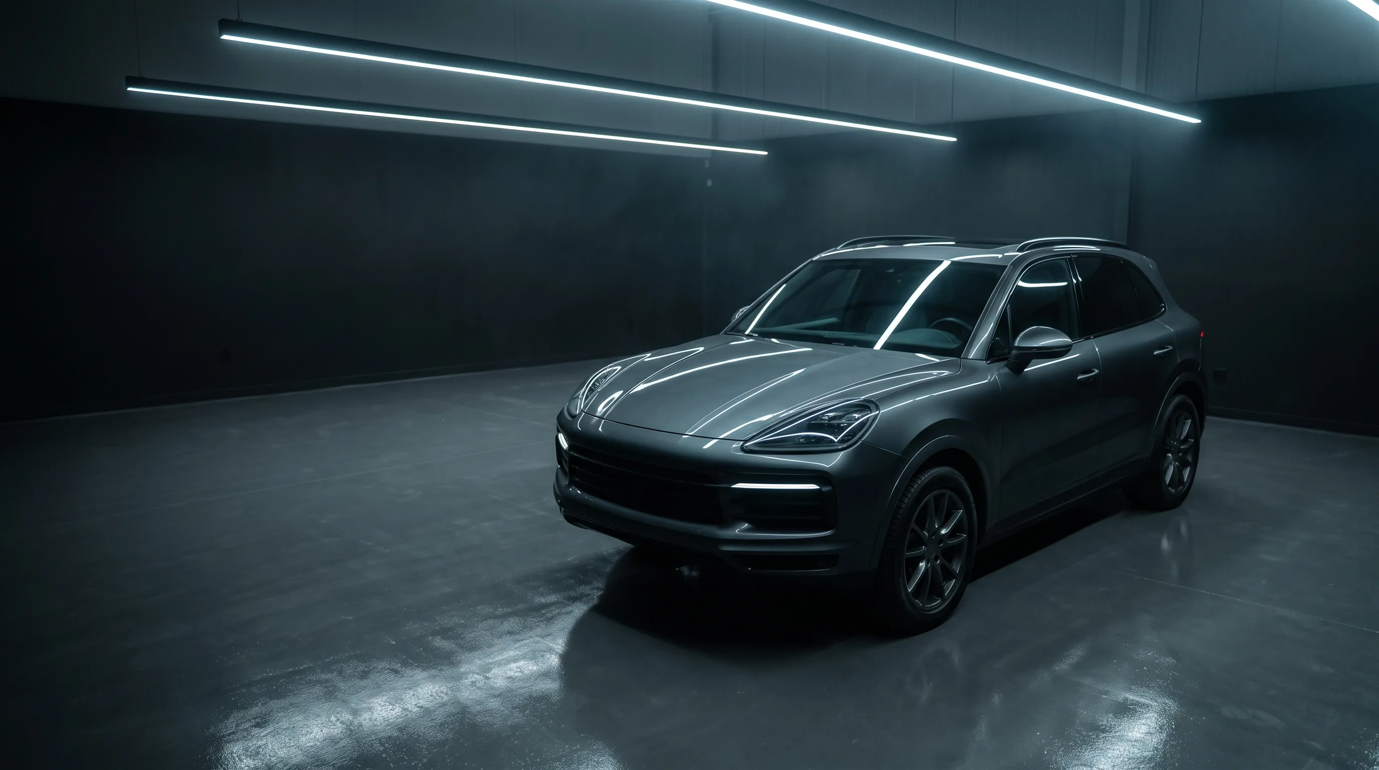 Charcoal SUV parked in a dark detailing studio under linear LED lights.
